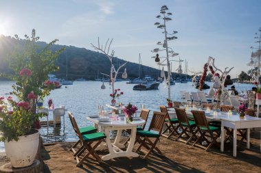 Gumusluk, Bodrum sahilindeki restoran ve bougainvillea çiçekleri. Güzel Ege Denizi yakınlarındaki Bodrum kasabasında renkli sandalyeler, masalar ve çiçekler.