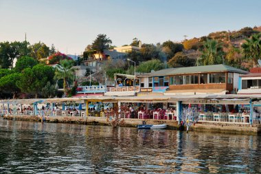 Gumusluk, Bodrum sahilindeki restoran ve bougainvillea çiçekleri. Güzel Ege Denizi yakınlarındaki Bodrum kasabasında renkli sandalyeler, masalar ve çiçekler.