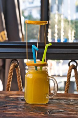 Taze sıkılmış organik portakal suyu. Özel olarak hazırlanmış portakal suyu. Tahta masaya dekore edilmiş egzotik alkollü kokteyller. Tahtada turuncu ve sarı pembe meşrubatlar.