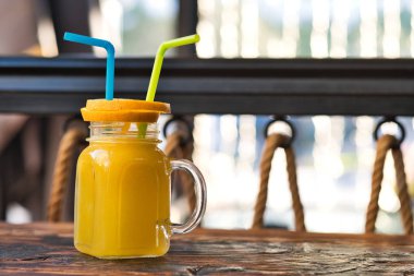 Taze sıkılmış organik portakal suyu. Özel olarak hazırlanmış portakal suyu. Tahta masaya dekore edilmiş egzotik alkollü kokteyller. Tahtada turuncu ve sarı pembe meşrubatlar.