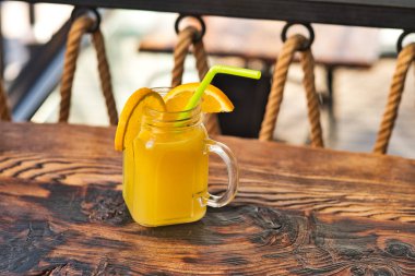 Taze sıkılmış organik portakal suyu. Özel olarak hazırlanmış portakal suyu. Tahta masaya dekore edilmiş egzotik alkollü kokteyller. Tahtada turuncu ve sarı pembe meşrubatlar.