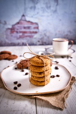 Kahverengi kahve çekirdekleri ve sıcak kahve. Tahta masadaki çikolatalı kurabiyeler çok güzel. Çikolata parçalı kurabiyeler Vintage Renkli. 