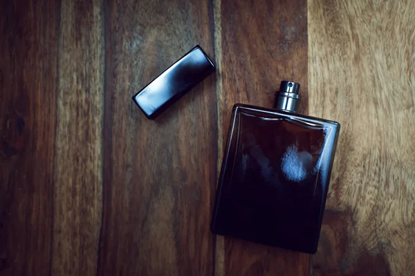 Sticlă neagră de pefume în fundal din lemn — Fotografie, imagine de stoc