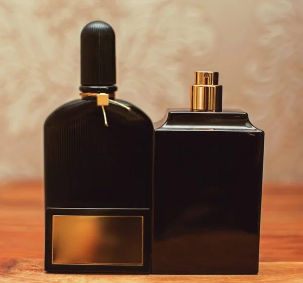 Duas garrafas pretas de perfume em fundo de madeira — Fotografia de Stock