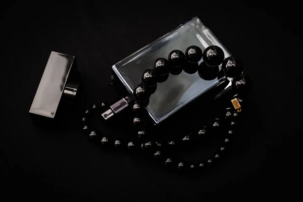 A sötét háttér előtt fekete gyöngyökkel parfüm — Stock Fotó