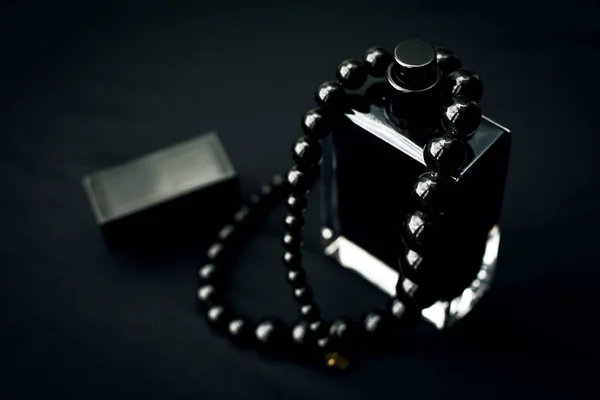Perfumy z czarnych paciorków na ciemnym tle — Zdjęcie stockowe