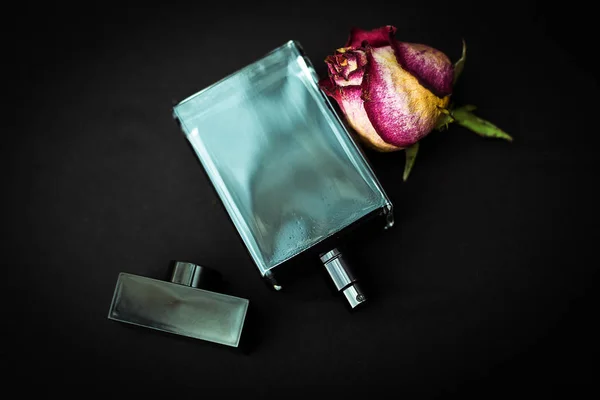 Perfume bottle with flowers on black background — Stock Photo, Image