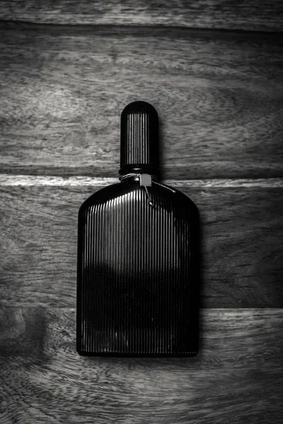 Frasco negro de perfume en fondo de madera —  Fotos de Stock