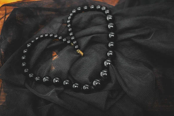 Stylish black beads in veil background — Stock Photo, Image