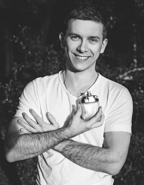 young man with male perfume over nature background