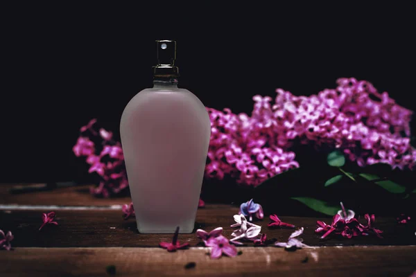 Парфумерна пляшка з бузковими квітами — стокове фото