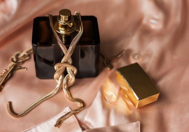 Parfüm şişesi ile pembe arka planda altın kolye