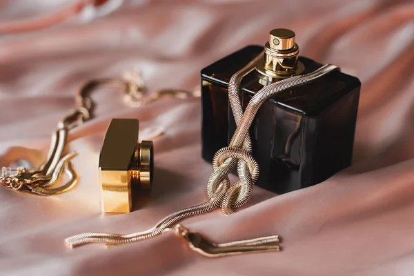 Butelki perfum naszyjnik złoty w różowym tle — Zdjęcie stockowe