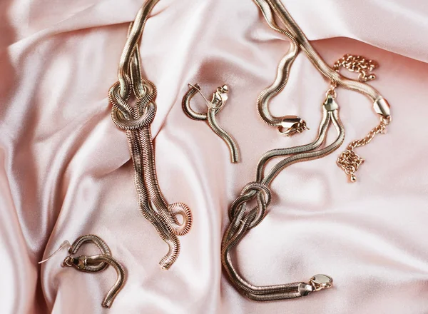 Ženské zlaté šperky v růžové pozadí — Stock fotografie
