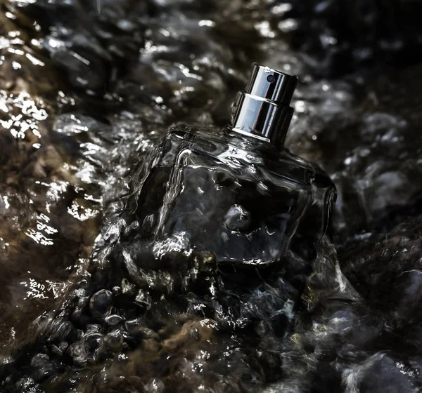 Botella de perfume en agua salpicada — Foto de Stock