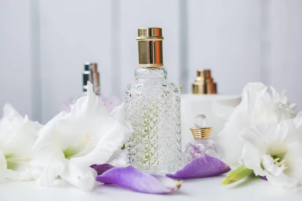 Olika flaskor parfym med vita blommor — Stockfoto