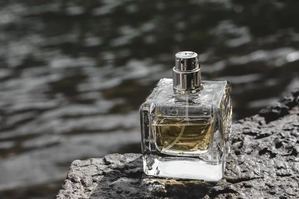 Парфюмерная бутылка на фоне воды — стоковое фото