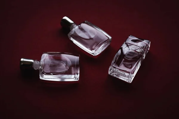 Różne małe butelki perfum w czerwonym tle — Zdjęcie stockowe