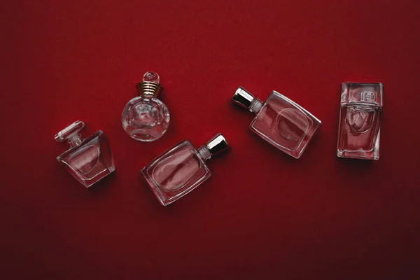 Botella pequeña diferente de perfume en fondo rojo — Foto de Stock