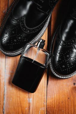 Erkek ayakkabısı ve parfümü ahşap arka planda