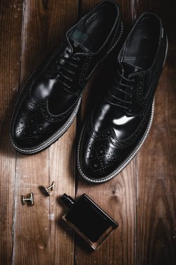 Erkek ayakkabısı ve parfümü ahşap arka planda
