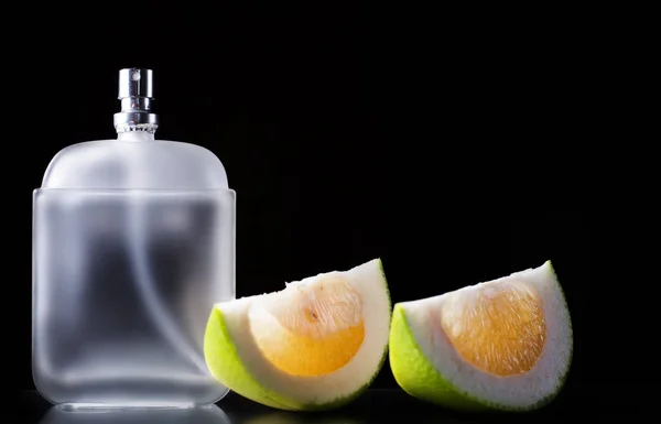 Botella de perfume masculino moderno y rodajas de cítricos sobre fondo oscuro —  Fotos de Stock