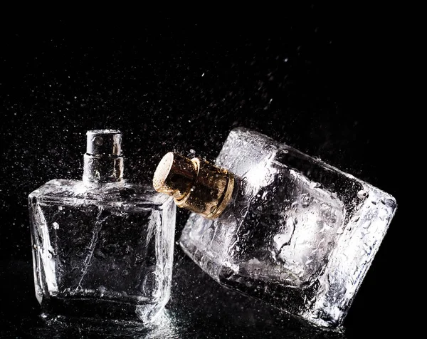 Três garrafas de perfumes sobre fundo preto — Fotografia de Stock