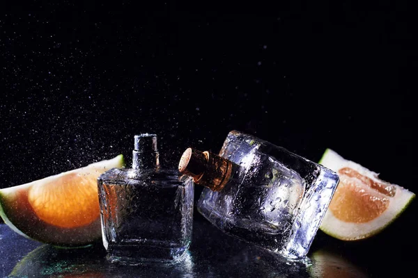 Дві пляшки парфумів з цитрусовими над чорним — стокове фото