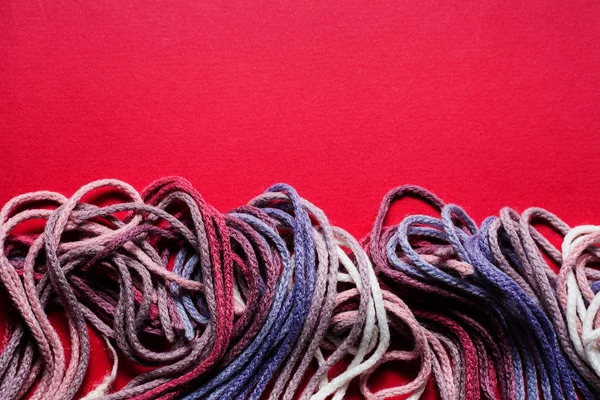 Colorful sewing threads on red background — Stock Photo, Image