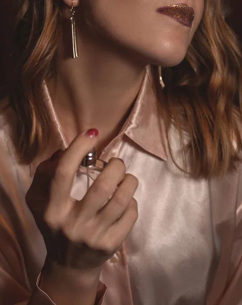 Hermosa joven con botella de perfume sobre fondo oscuro — Foto de Stock