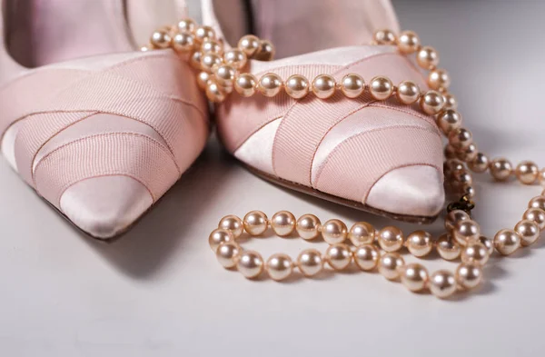 Pair of ladies pink high heels with long strand of white pearls Stock Picture