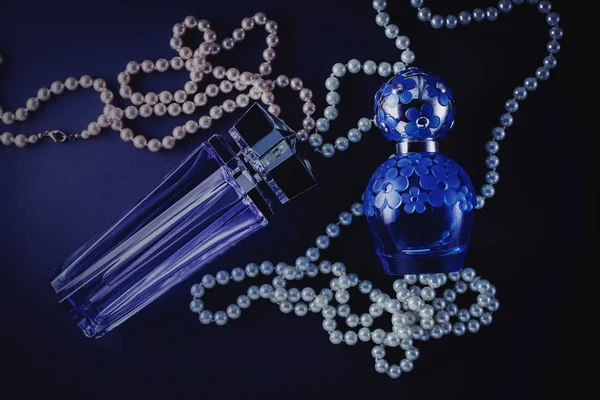 Perfume femenino sobre fondo azul con perlas —  Fotos de Stock