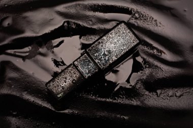 Islak arkaplanda siyah parfüm 