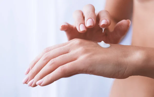 Žena hydratuje její ruku kosmetickým krémem krém — Stock fotografie