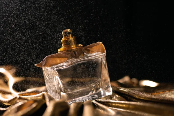 Rozpylanie butelek perfum na ciemnym tle — Zdjęcie stockowe