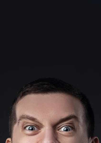 Böse Augen eines guckenden Mannes auf dunklem Hintergrund — Stockfoto