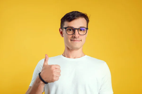 Chico muestra un pulgar sobre un fondo amarillo —  Fotos de Stock