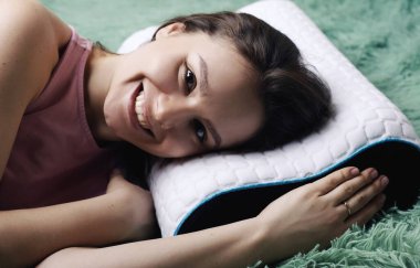 Ortopedik yastıkla yatakta yatan genç bir kadın. Sağlıklı duruş kavrayışı