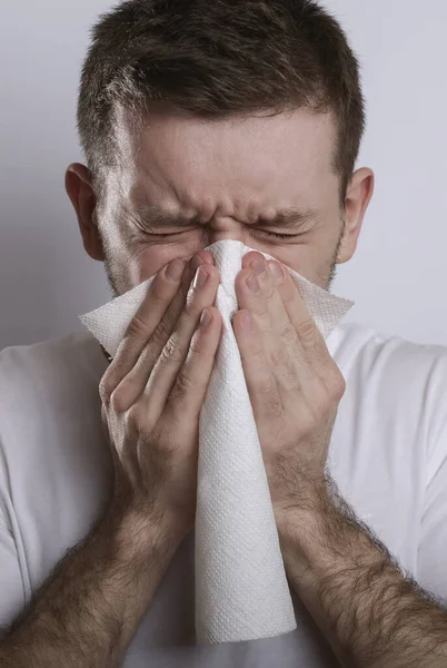 Ill man sneezes into a napkin