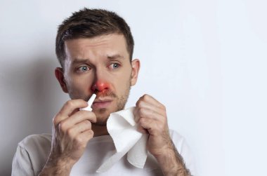 Hasta alerjik genç adam burun damlası damlatıyor, kırmızı gözleri ve burnu var, bitkiye alerjisi var.