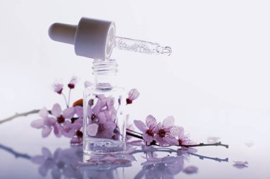 Bir şişe pipetli ve bahar çiçekli hyaluronik asit.