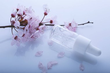 Bir şişe pipetli ve bahar çiçekli hyaluronik asit.