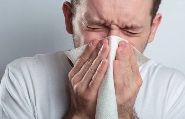 Mendilli genç bir adam. Hasta adamın burnu akıyor. İnsanoğlu soğuk algınlığına çare bulur.