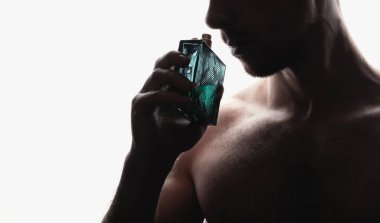 Adam beyaz arka planda parfüm kokusu alıyor.