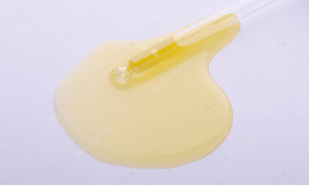 Liquid yellow gel or serum on grey background