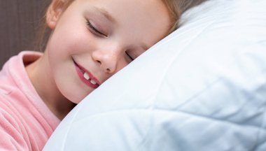 Sevimli küçük kız uyuyor ve yastığa sarılıyor.
