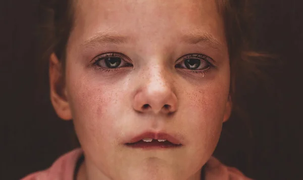 Tears in the eyes of a child. The girl is crying and a tear runs down his cheek. Close-up.