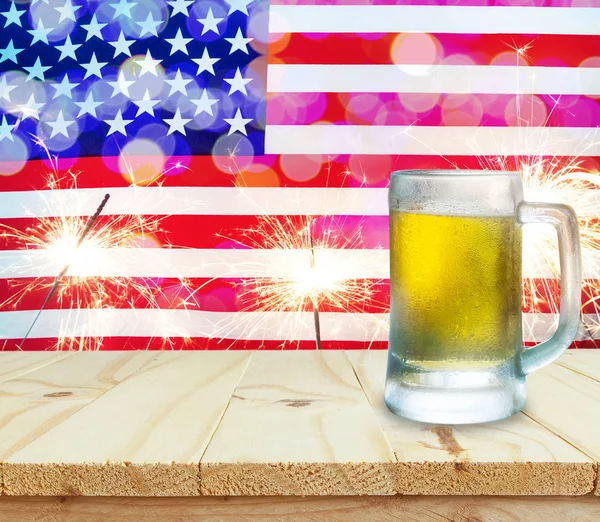 Ποτήρι μπύρα στο ξύλινο τραπέζι. Σημαία των ΗΠΑ με φόντο βεγγαλικά — Φωτογραφία Αρχείου