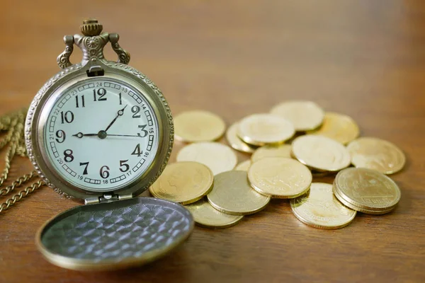 Montre de poche vintage dorée avec pile sur fond de table en bois — Photo