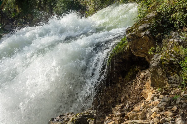 El rápido flujo de agua contra rocas y árboles . — Foto de Stock